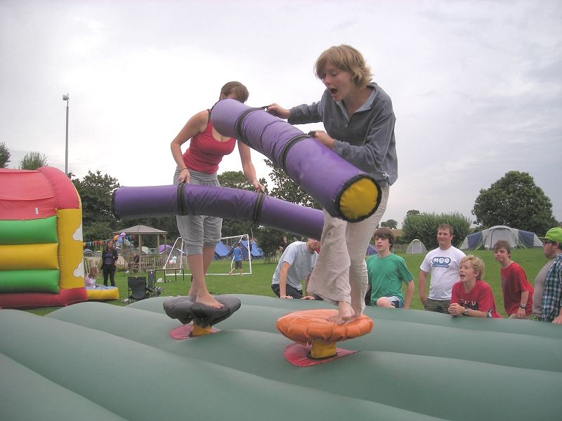 Fi knocks Sarah off the bouncy castle with a puddle stick.